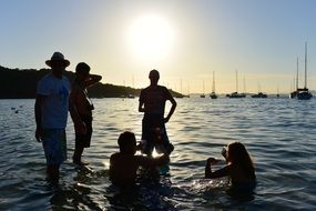 silhouettes of friends in the water at sunset