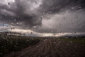 Beautiful grey clouds above the landscape through the window with raindrops