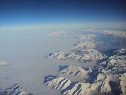 snowy mountain peaks above clouds, aerial view