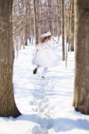 little girl running in a snowy forest on a sunny day