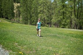 child runs in a green meadow in forest
