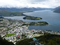 town on coast in view of scenic mountains, new zealand, queenstown