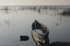 weathered rowing boat on calm water at shore