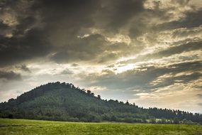 cloudy sky over a green hill