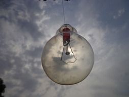 Light bulb against the sky with clouds