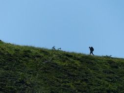 man with a backpack on a green hill