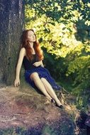 girl sitting under a tree in the forest