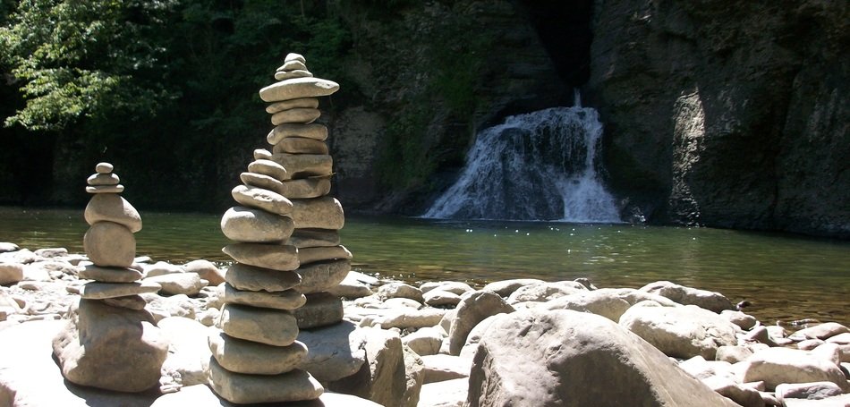 tower of stones on a lake with a waterfall