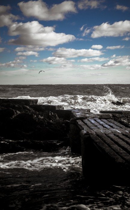 pier on stones in grey sea under blue sky