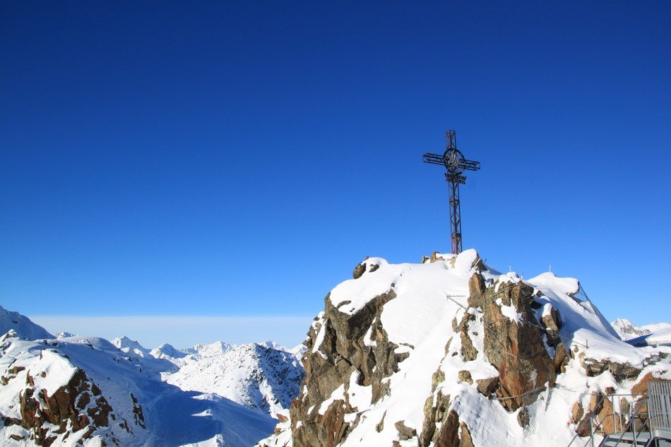 cross on snowy alpine rocks, austria, tyrol