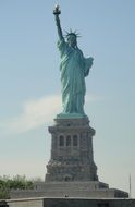 Statue of Liberty in New York against the blue sky with white clouds