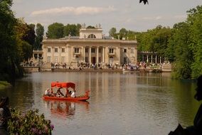 red boat with people on the lake in the park, poland, warsaw