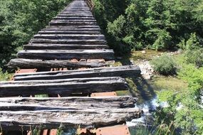 weathered wooden bars on bridge above forest river, concept of anxiety