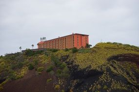 Red building hotel on green hill