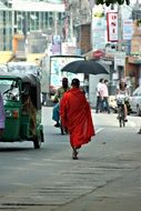 monk with umbrella walks on a city street in Sri Lanka