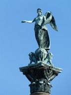 statue of an angel with lions on a blue sky background
