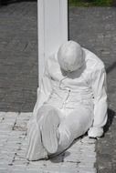 reclining man like a white statue in the middle of the street