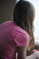 young girl looking at window