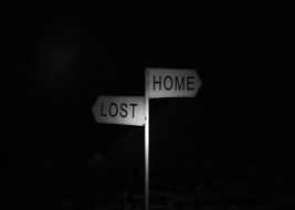 Road sign "lost", "home" in the dark