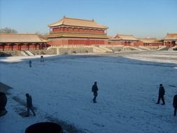 people walk in the snow near the palace in peking