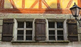 two wooden windows with shutters on aged wall