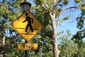 pedestrian sign hanging on a street lamp