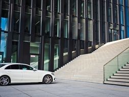 White car near a modern mirror skyscraper
