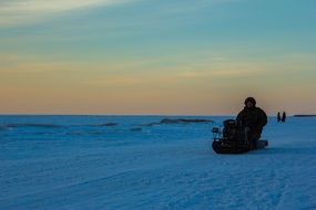 man rides through the snow on a snowmobile