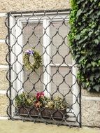 A wall with a barred window among the flowers