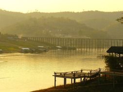 panorama of a pier and a wooden bridge over a river against the backdrop of foggy countryside in Thailand