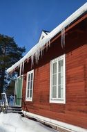 wooden house with icicles on the roof in winter