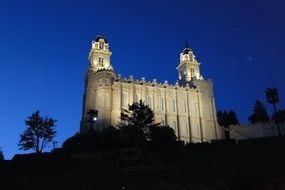 night lights of the Manti Temple with silhouettes on blue sky background