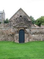 stone wall with wooden door on the green field