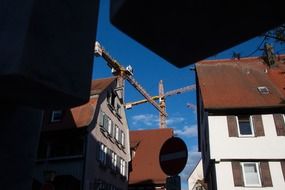 gables of houses on the background of construction cranes