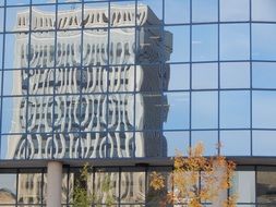 reflection of grey modern building on glass facade in a city