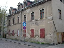 Shabby facade of an old building with closed window shutters