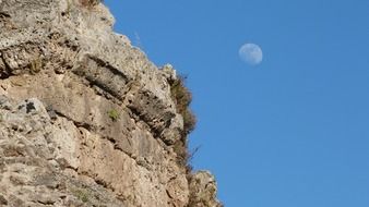 moon in the blue sky over a stone building