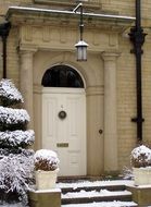 Snowy plant in front of white entrance door to the house in England