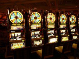 row of colorful gambling machines in darkness