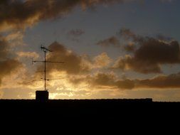 picture of antenna on the roof of the house at sunrise