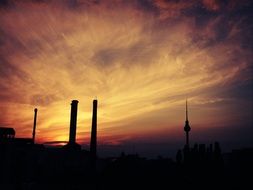 chimneys and spire of tv tower in sunset sky, germany, berlin