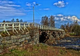 old stone bridge with wooden railing across river, finland