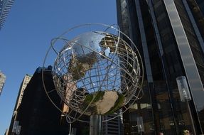 globe-shaped monument against the background of a skyscraper