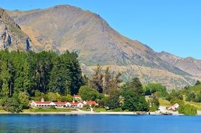 distant view of houses with red roofs on the shore of a mountain lake