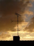 antenna on the roof of the house on a background of clouds