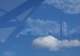 reflection of city buildings and clouds in the glass roof of a bus stop in Uppsala, Sweden