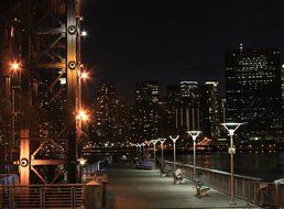 people rest on illuminated waterfront of modern city at night