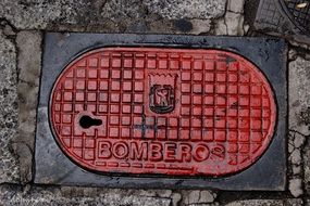 red sewer manhole on pavement in madrid