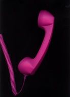 pink telephone receiver on a black background