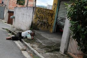 man sleeping on dirty street, brazil, carapicuiba city, favela